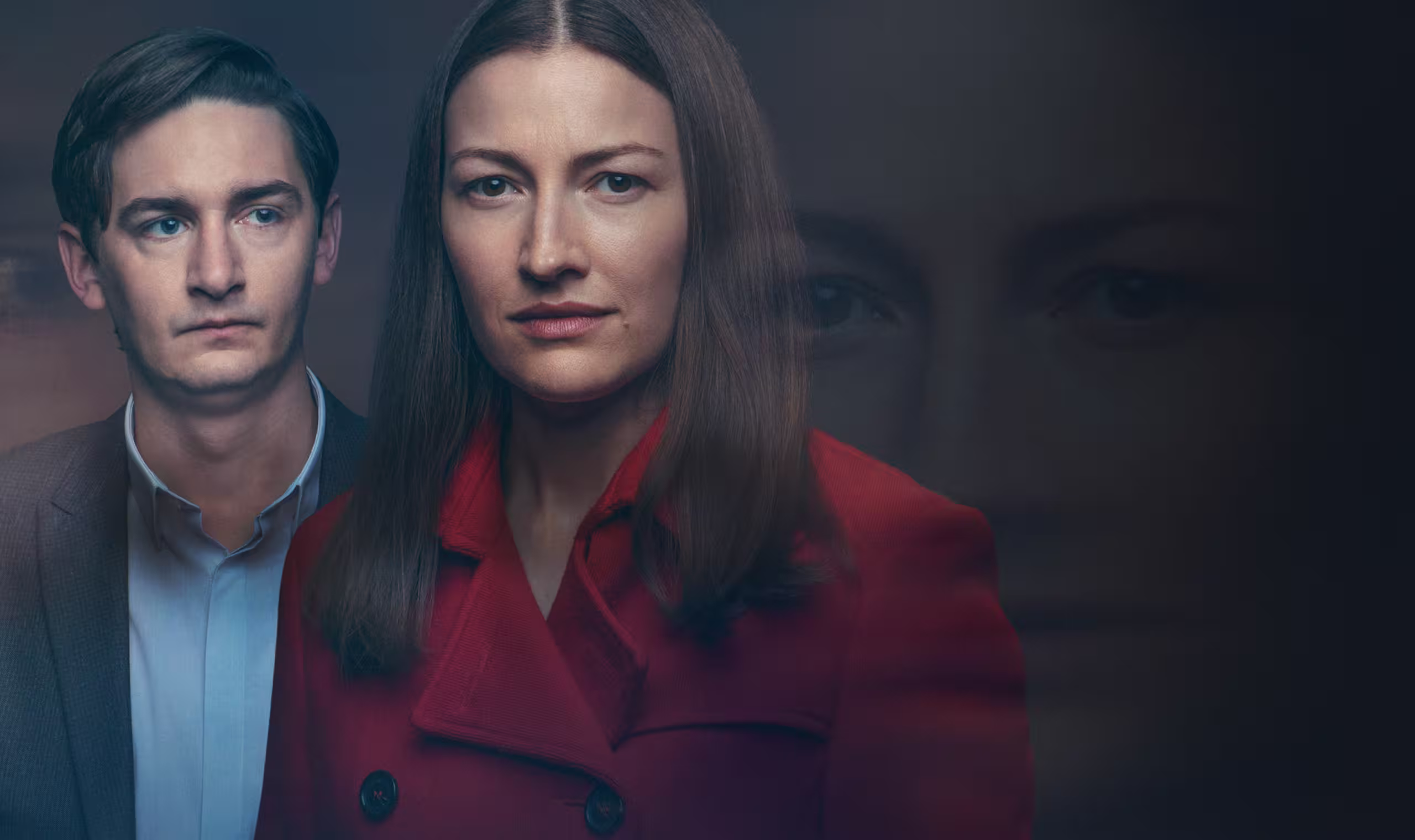 Man in a suit standing next to a woman wearing a red coat.